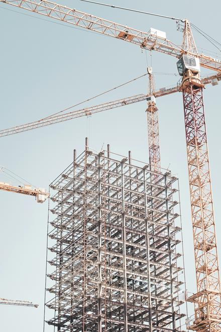 Steel building frame under construction with tower cranes