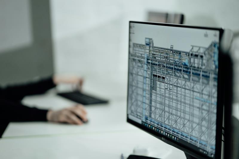 Engineer at a monitor showing a 3D steel structure model